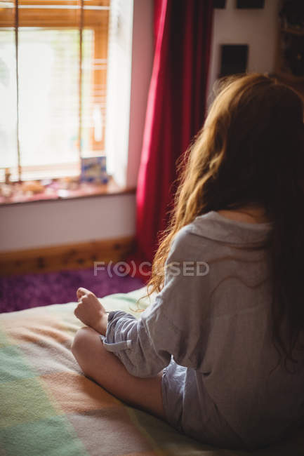 Rückansicht einer Frau, die zu Hause auf dem Bett sitzt — Stockfoto