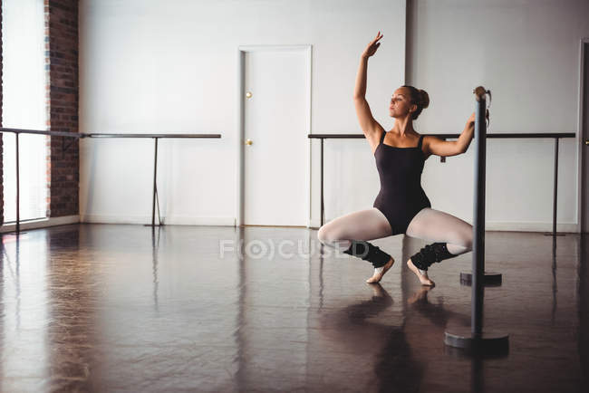 Bailarina practicando ballet en barra en estudio de ballet - foto de stock