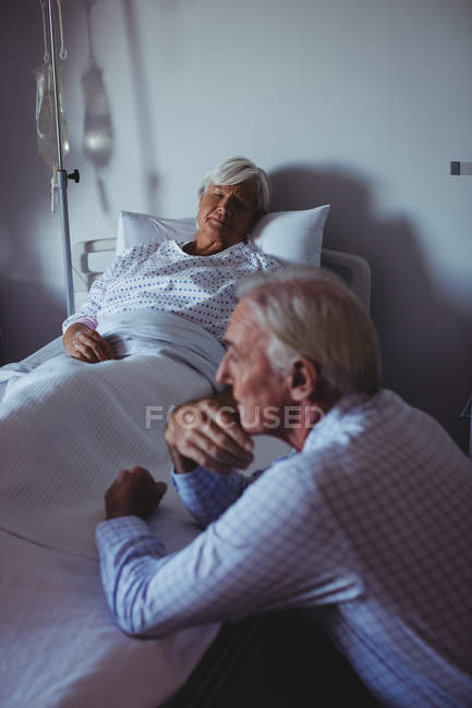 Хіба жінка спить на ліжку, а турбується чоловік сидить поруч зі своїм ліжком в лікарні — стокове фото
