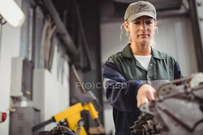 Mecánica femenina revisando las piezas de un coche en el garaje de reparación - foto de stock