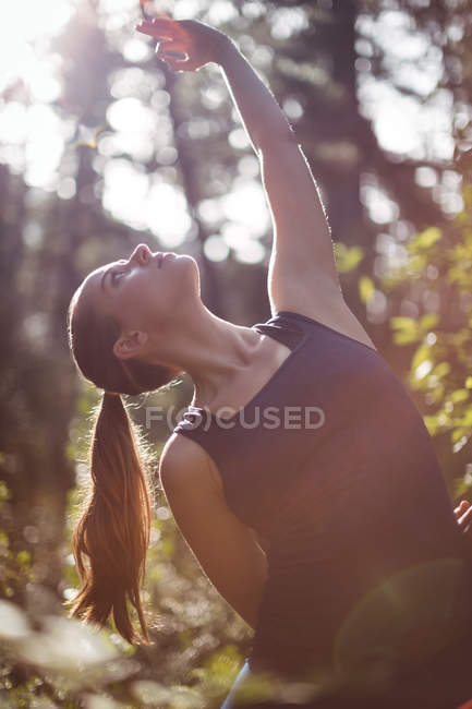 Женщина, занимающаяся йогой в лесу в солнечный день — стоковое фото