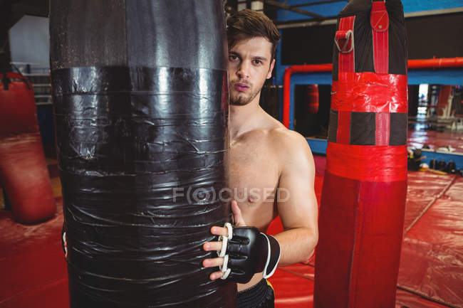 Retrato de boxeador segurando saco de perfuração no estúdio de fitness — Fotografia de Stock