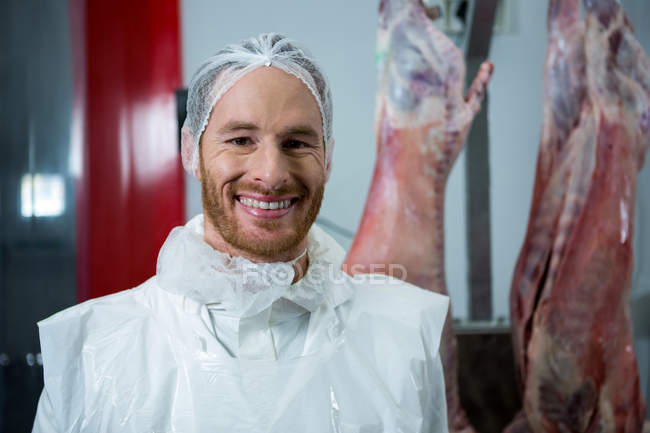 Porträt eines in die Kamera lächelnden Metzgers in der Fleischfabrik — Stockfoto
