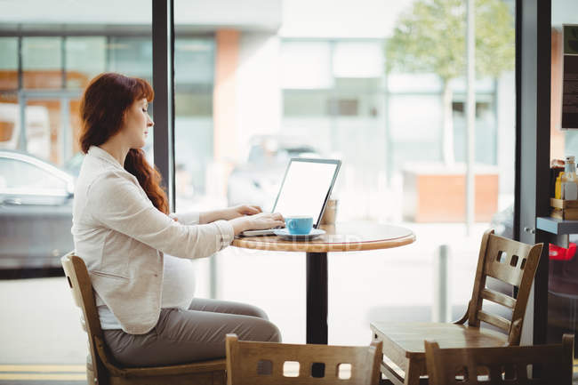 Grávida empresária usando laptop no escritório cafetaria — Fotografia de Stock