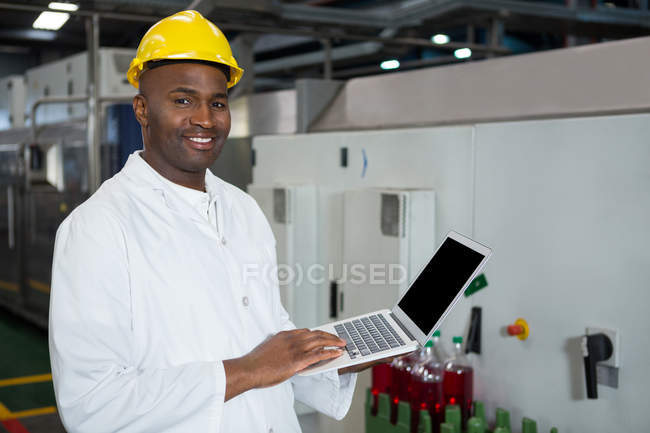 Confident male worker using laptop in juice factory — Stock Photo