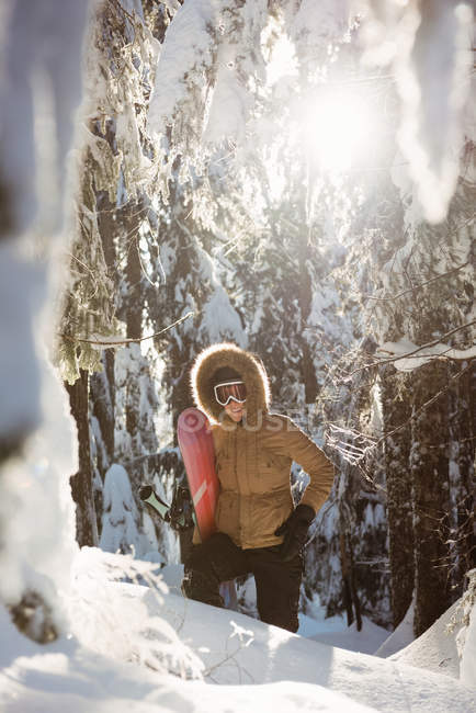Woman with snowboard walking on snow covered mountain — Stock Photo