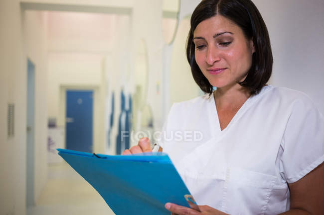 Dentista mulher escrevendo relatório médico na clínica — Fotografia de Stock