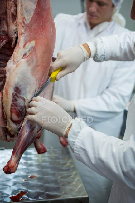 Мясники режут мясо на мясокомбинате, обрезают — стоковое фото