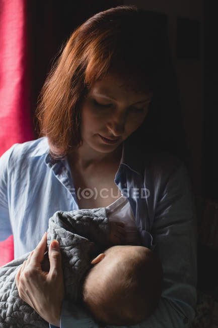 Мати грудного вигодовування дитини в спальні вдома — стокове фото
