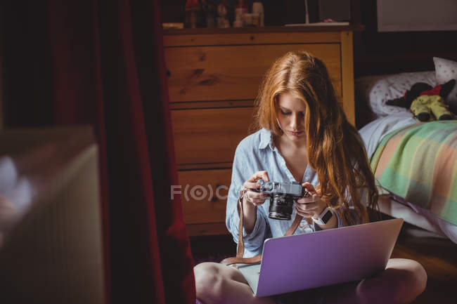 Bella donna guardando le immagini sulla fotocamera digitale a casa — Foto stock