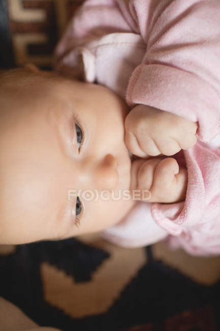 Close-up of cute baby holding fists indoors — Stock Photo