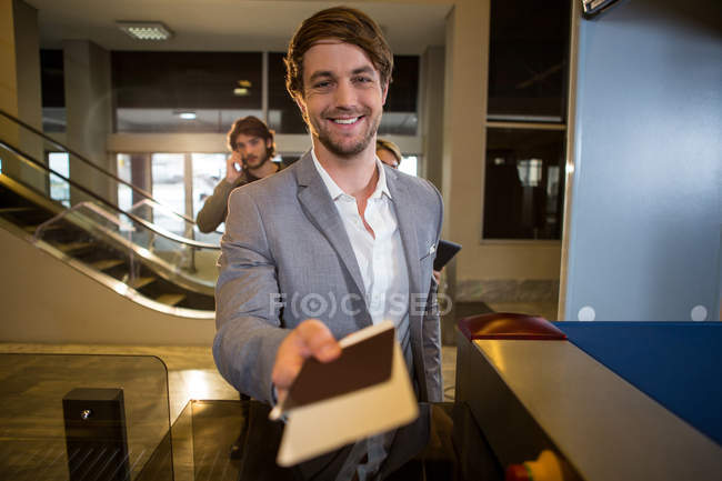 Empresário entregando o cartão de embarque no balcão no terminal do aeroporto — Fotografia de Stock