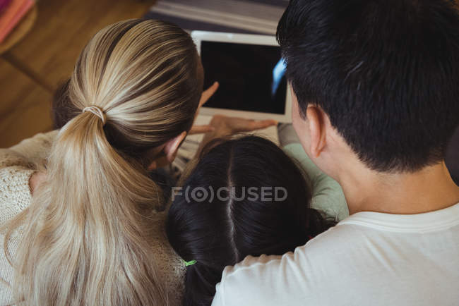 Visão traseira da família usando tablet digital na sala de estar — Fotografia de Stock