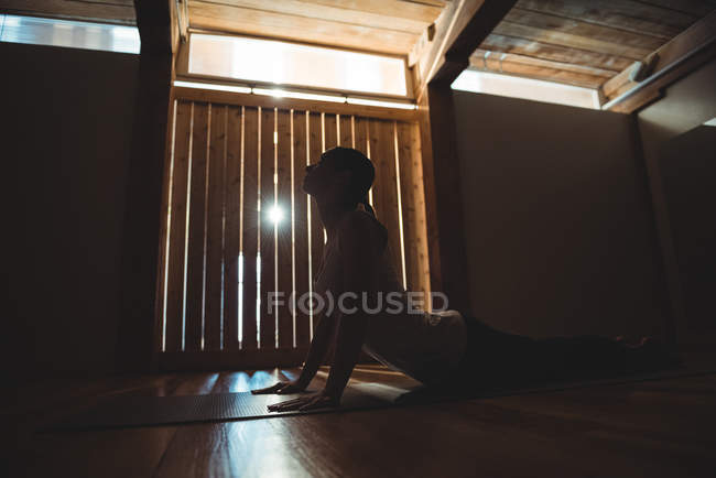 Vista lateral da mulher praticando ioga no estúdio de fitness — Fotografia de Stock