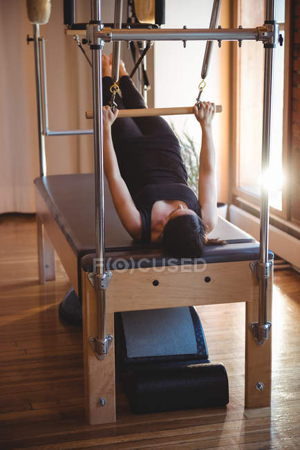 Mujer practicando en un reformador de pilates en un gimnasio - foto de stock