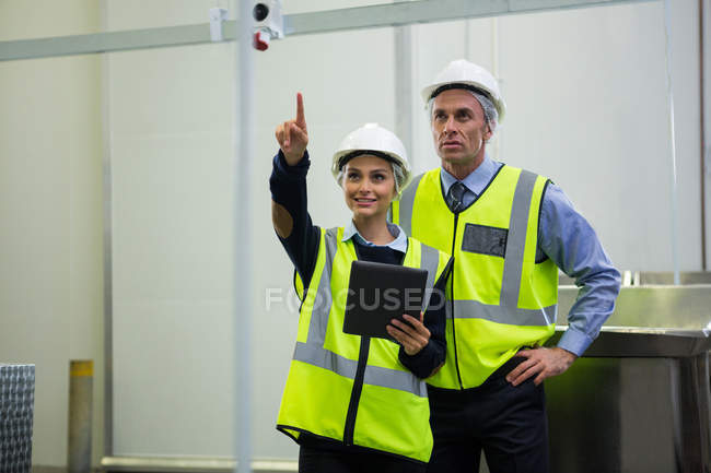 Two technicians discussing over digital tablet at meat factory — Stock Photo