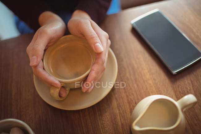 Partie médiane de la femme tenant une tasse de café dans le café — Photo de stock