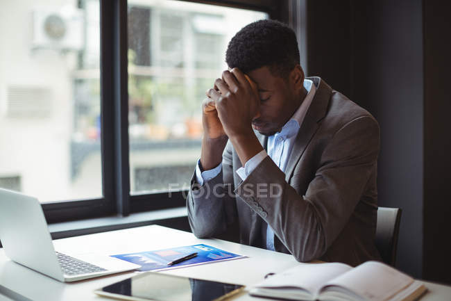 Стрессовый бизнесмен сидит за своим столом в офисе — стоковое фото