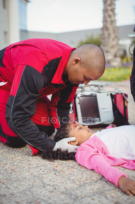 Paramédicos examinando menina ferida na rua — Fotografia de Stock