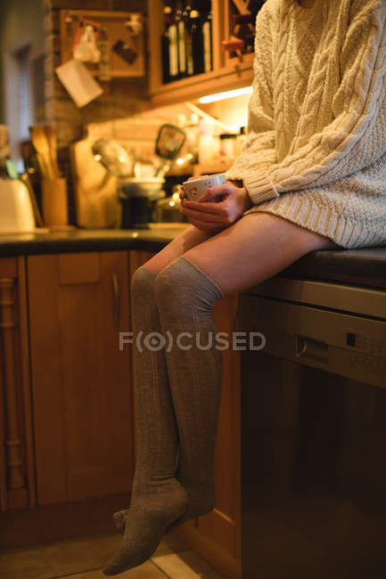 Retrato de mulher segurando uma xícara de café na cozinha em casa — Fotografia de Stock