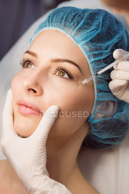 Крупный план женщины, получающей инъекцию лица в клинике — стоковое фото