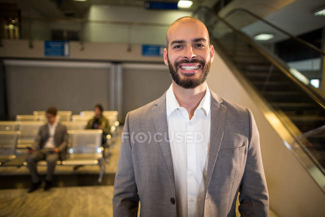 Бизнесмен улыбается перед камерой в аэропорту — стоковое фото