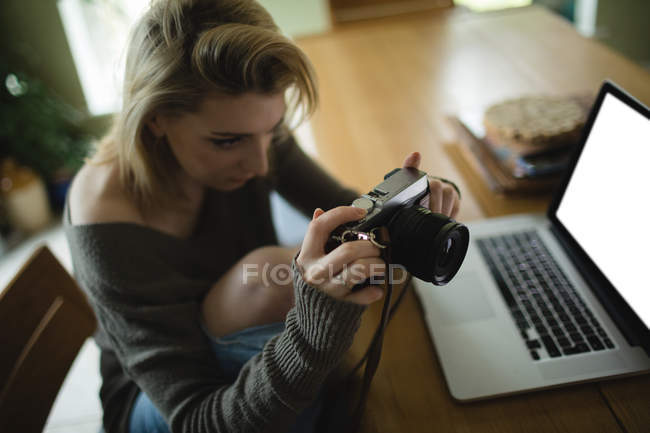 Mulher olhando para fotos na câmera digital na sala de estar em casa — Fotografia de Stock