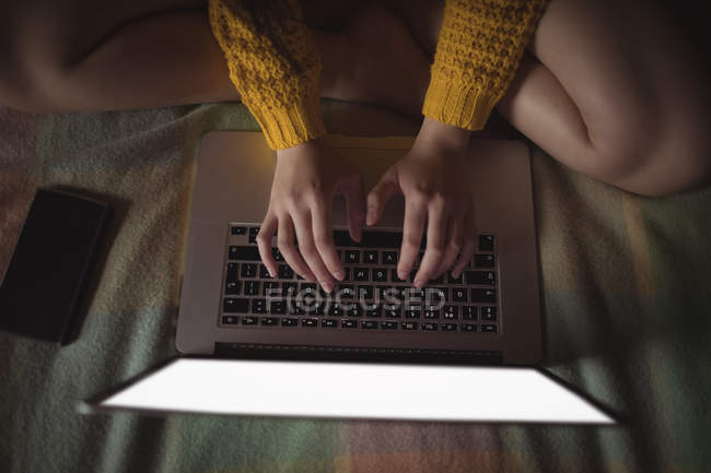 Vista ritagliata della donna che utilizza il computer portatile sul letto in camera da letto — Foto stock