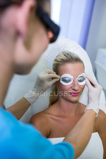 Dermatologista ajustando óculos de proteção no salão de beleza — Fotografia de Stock