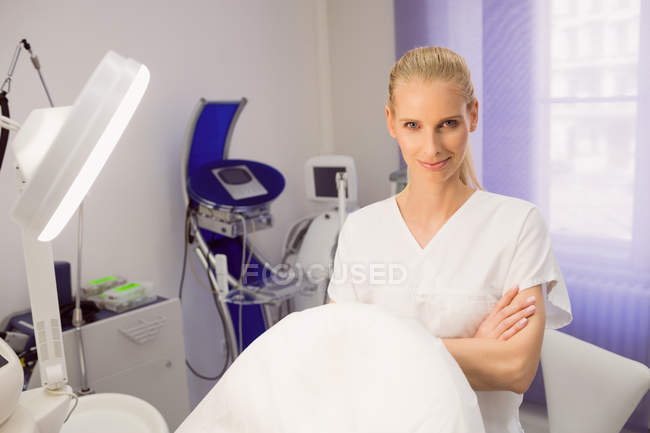 Вид улыбающегося врача, стоящего со скрещенными руками в клинике — стоковое фото