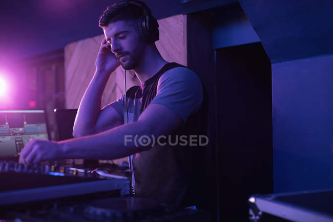 Masculino dj ouvindo fones de ouvido enquanto tocando música no bar — Fotografia de Stock