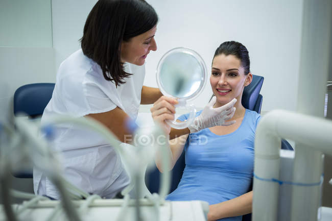 Доктор вивчає жіночу шкіру обличчя пацієнта в клініці — стокове фото