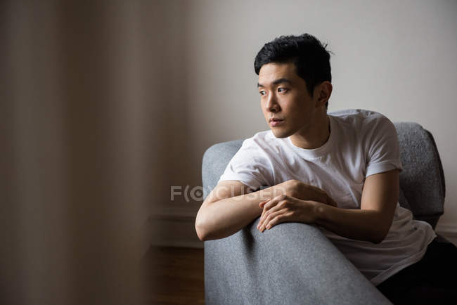 Homem atencioso olhando pela janela em casa — Fotografia de Stock