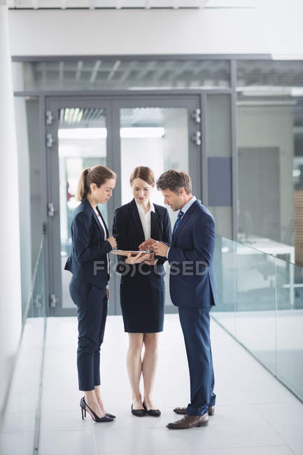 Uomo d'affari e collega discutono su tablet digitale all'interno di un edificio per uffici — Foto stock