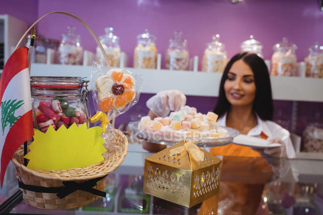Female shopkeeper serving turkish pastries in plate at counter in shop — Stock Photo
