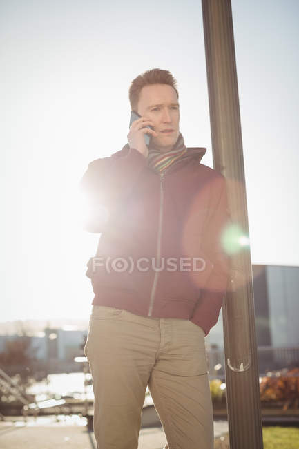 Male executive talking on mobile phone on street in front of office building — Stock Photo