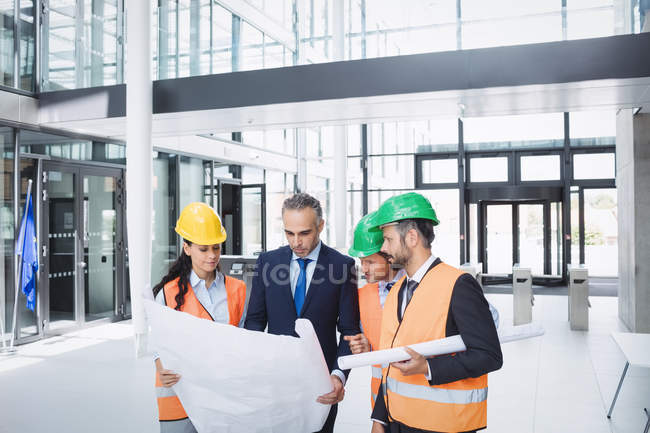 Businessman discussing on blueprint with architects in office building — Stock Photo