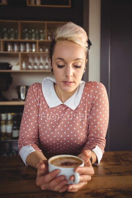 Femme tenant tasse de café dans le café — Photo de stock