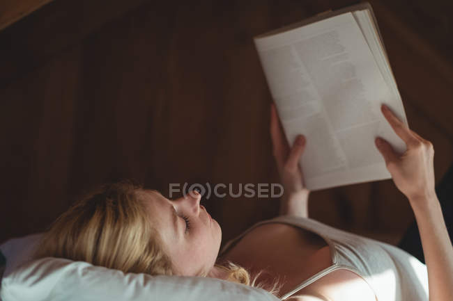 Schöne Frau liegt auf dem Bett und liest zu Hause im Schlafzimmer Magazin — Stockfoto
