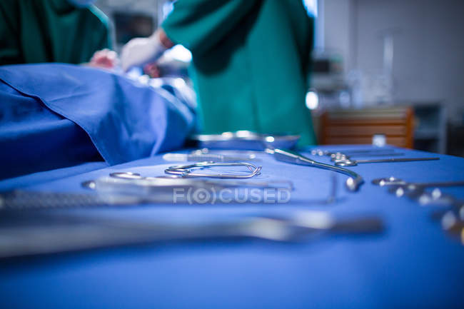 Хирургические инструменты на хирургическом подносе с хирургом на заднем плане в операционном зале больницы — стоковое фото