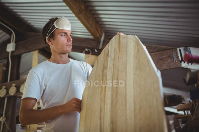 Чоловік робить дошку для серфінгу в інтер'єрі майстерні — стокове фото