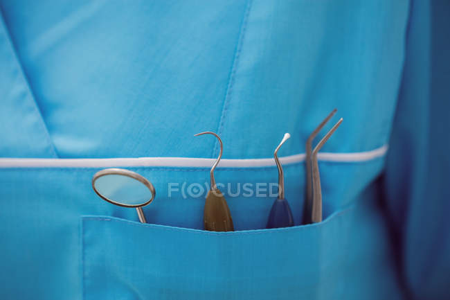 Seção média do dentista carregando ferramentas odontológicas no bolso na clínica odontológica — Fotografia de Stock