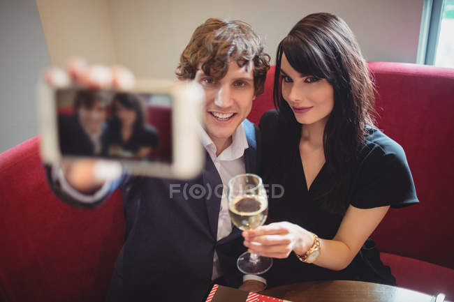 Couple tenant boire et prendre un selfie au restaurant — Photo de stock