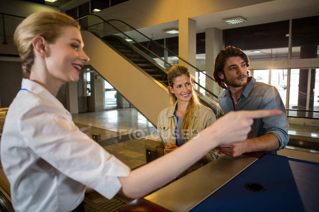 Female staff guiding passengers in the airport terminal — Stock Photo