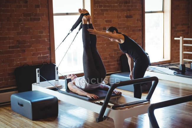 Trainer assisting woman while practicing pilates in fitness studio — Stock Photo