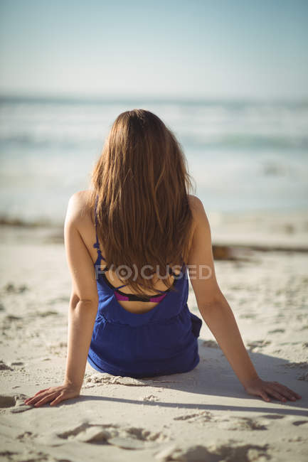 Vista trasera de la mujer relajándose en la playa en un día soleado - foto de stock