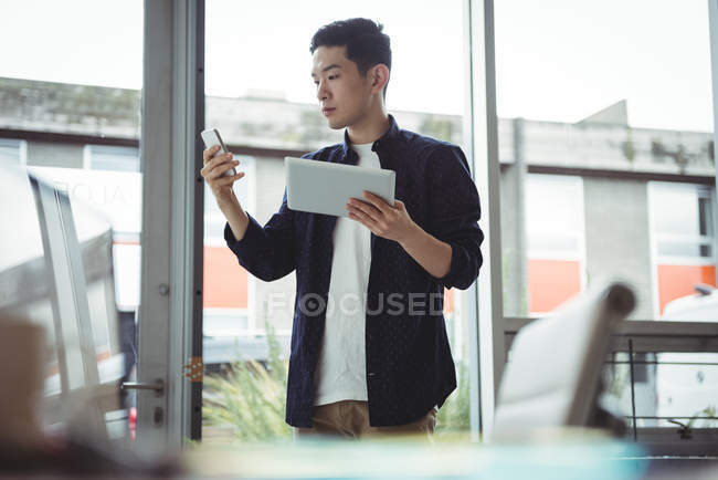 Бизнес-руководитель с помощью мобильного телефона и цифрового планшета в офисе — стоковое фото