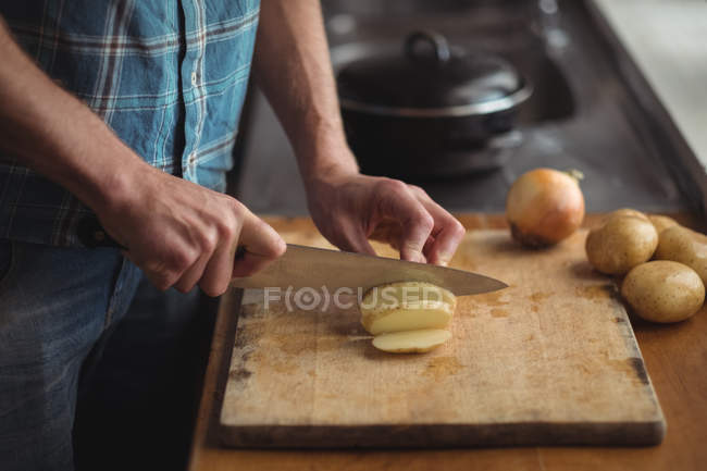 Section médiane de l'homme coupant des tomates sur la planche à découper dans la cuisine — Photo de stock