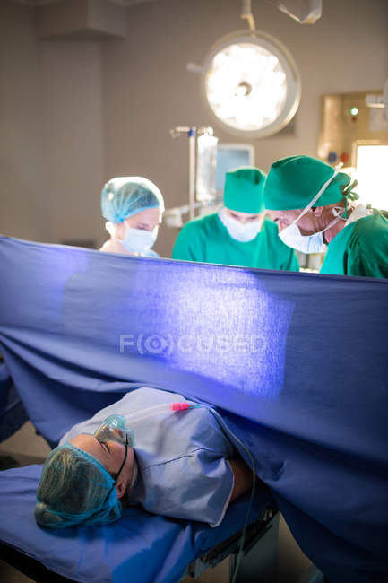 Equipe médica examinando a mulher grávida durante o parto na sala de cirurgia — Fotografia de Stock