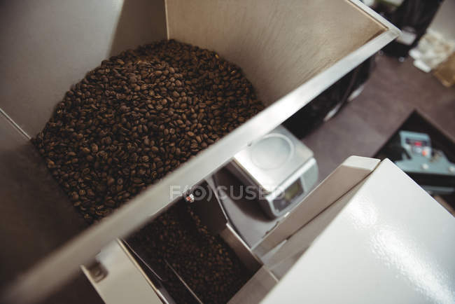 Кофе-бобы наливают внутрь кофе обжига машина в кафе — стоковое фото
